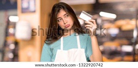 Girl with apron taking a credit card without money in a bakery