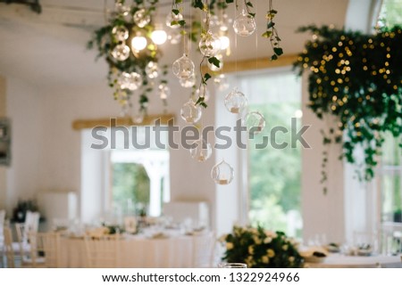 Little balls with candles hang from floral garland over wedding dinner table