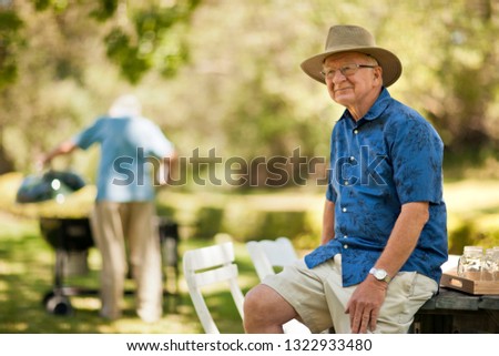 Thoughtful senior man sitting on a picnic table in a park.