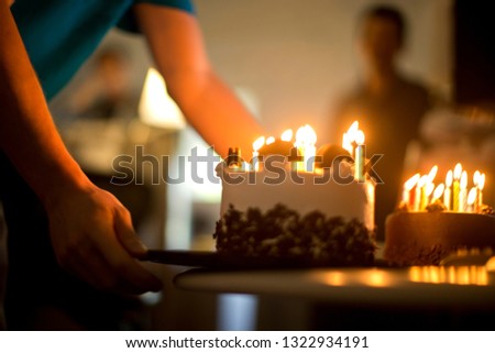 Arms of a mid adult man placing a glowing birthday cake on a table.
