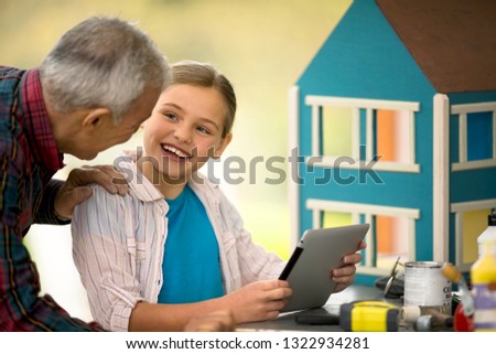 Happy senior man and his young granddaughter looking at a digital tablet.