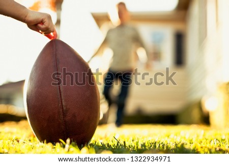 Running boy playing football in the backyard with his friend.