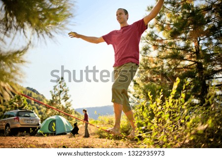 Mid-adult man practices balancing on rope on mountain top.