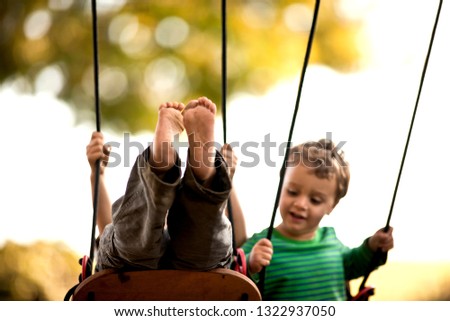 Boys playing on a swingset. Royalty-Free Stock Photo #1322937050