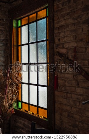 Antique window with colors on a brick wall with some dried ornamental plants