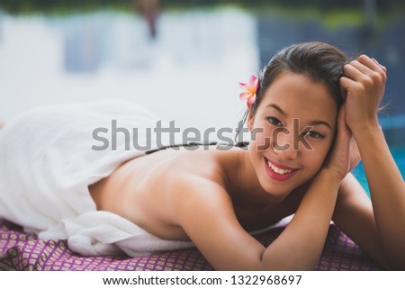 Spa Stone Massage concept, Close up of beautiful young asian woman Getting traditional spa hot stones massage in pool spa resort, Thailand