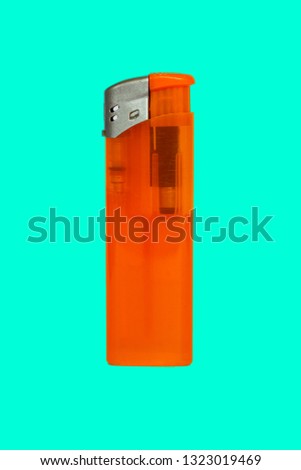 Cheap orange plastic gas disposable cigarette lighter, closeup, isolated on turquoise background. Studio photo. 