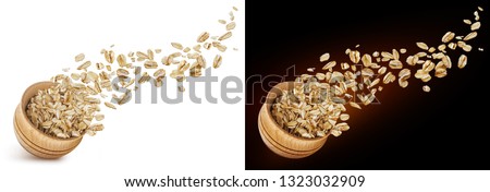 Oat flakes flying out of wooden bowl isolated on white and black background. Falling oats Royalty-Free Stock Photo #1323032909