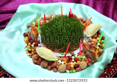 Traditional shekerbura, mutaki, shirinchorek, kata and pakhlava as Novruz symbol on xoncha on white background Azerbaijan holiday . Semeni . Candle . khoncha . In hell, hazelnuts, gooseberries