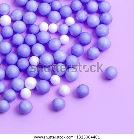 Blue and white balls are abstract scattered on the lilac surface