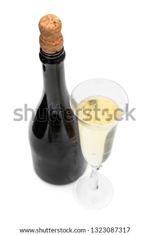 Bottle of champagne and glass of champagne on white.
