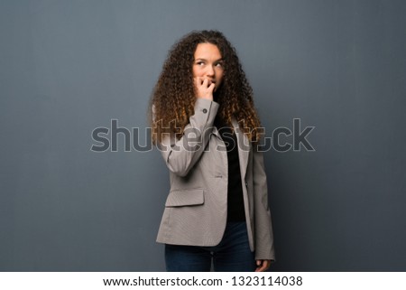 Teenager girl over blue wall nervous and scared putting hands to mouth