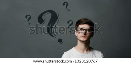 Portrait of thinkng young guy with question mark above his head.