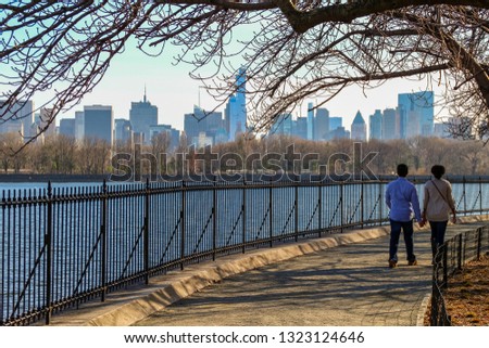 Happy couple walking in Central Park, New york city. Skyscrappers skyline.