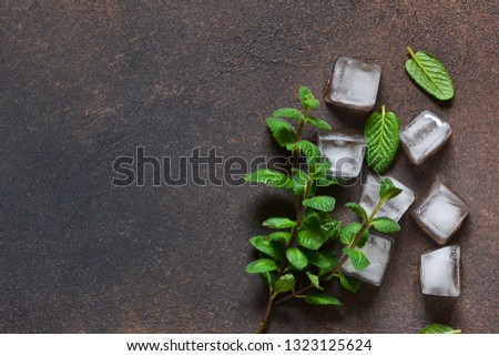 Cold ice and fresh mint on a concrete background. View from above.