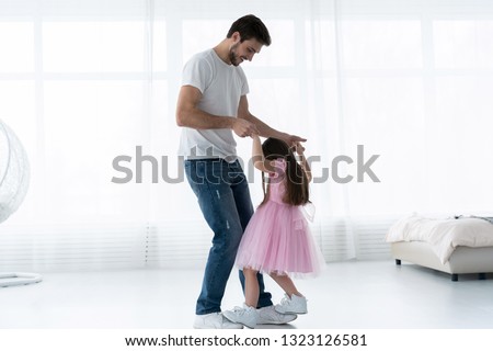 I love you, dad! Handsome young man is dancing at home with his little cute girl. Happy Father's Day!