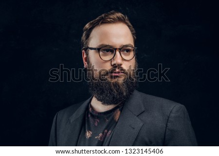 Close-up portrait of a smart bearded man in glasses in a dark studio
