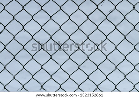 Mesh metal fence against the background of snow
