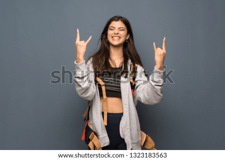 Teenager traveler girl over wall making rock gesture
