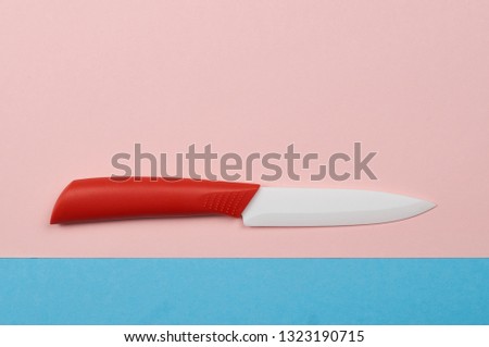 ceramic knife with red handle on pink and blue background