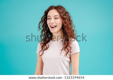 Attractive brunette girl with curly hair isolated over blue turquoise background smiling and laughing