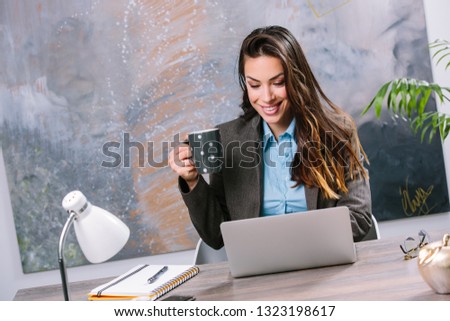 Young beautiful businesswoman working on laptop while sitting at her working place
