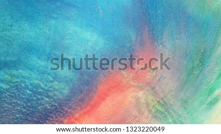 Colorful sparkling paints mix in beautiful patterns. Oil ink of red, blue, yellow and other colors spread on the surface and mix one into another creating amazing textures and design.