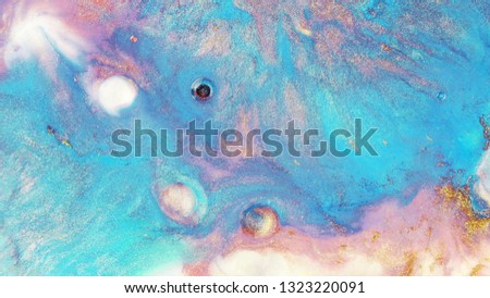 Colorful sparkling paints mix in beautiful patterns. Oil ink of blue, pink, gold, white and other colors spread on the surface and mix one into another creating amazing textures and design.