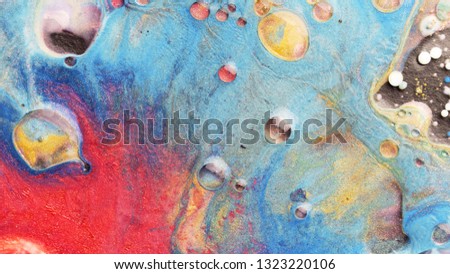 Colorful sparkling paints mix in beautiful patterns. Oil ink of coral, yellow, blue, orange and other colors spread on the surface and mix one into another creating amazing textures and design.