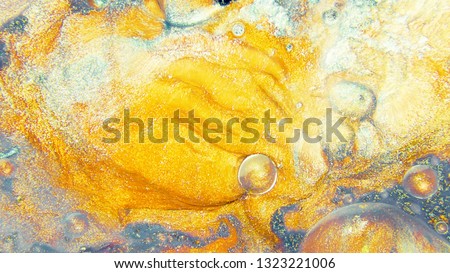 Colorful sparkling paints mix in beautiful patterns. Oil ink of yellow, grey and other colors spread on the surface and mix one into another creating amazing textures and design.