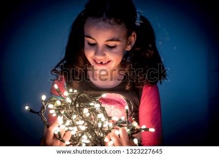 Pretty girl smiles happy and amazed surrounded by Christmas light.
