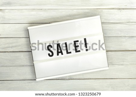 Light box with sale letters on white wooden table, top view