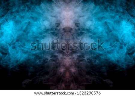 Mystical pattern of green, blue and pink colored smoke in the shape of a ghost's face with big eyes and an open mouth creating a feeling of fear on a black isolated background from a horror movie.