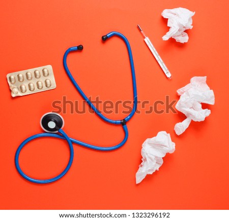 The concept of treating cold diseases. Used nasal wipes, thermometer, pills, stethoscope on orange background. Top view
