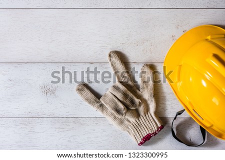 engineer or foreman safety helmet and glove on wooden table, showing love sign, top view