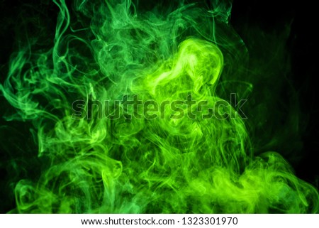 Thick colorful green smoke on a black isolated background. Background from the smoke of vape
