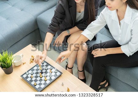 Business women moving chess figure with team behind - strategy, management or leadership concept.
