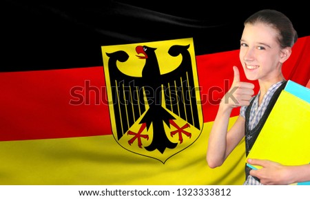 Happy young girl holding books, on the background of the flag of Germany