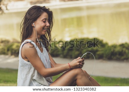 portrait of young woman listening to the music on the phone in the park