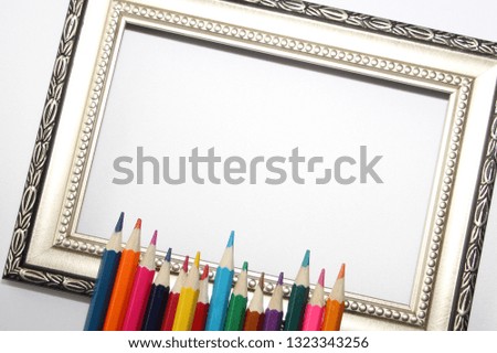 Vintage frame for paintings and colored pencils on a white background. Many colored pencils.