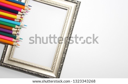 Vintage frame for paintings and colored pencils on a white background. Many colored pencils.