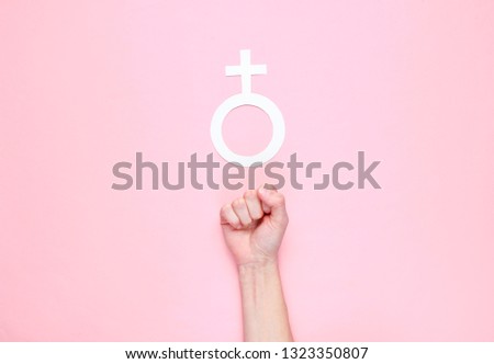 Feminism. Female fist, gender female sign on a pink background. Top view, minimalism