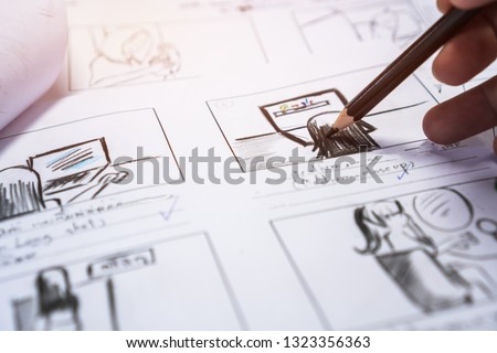 Hands on Storyboard movie layout for pre-production, storytelling drawing creative for process production media films. Script video editors and writing graphic in form displayed in maker shooting Royalty-Free Stock Photo #1323356363