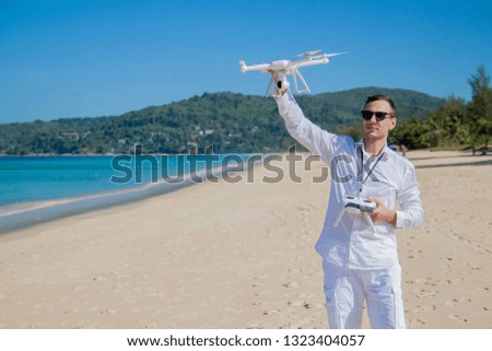 Man in a shirt operating a drone with remote control on the sea. 