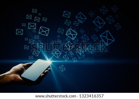 Hand holding smartphone with glowing letter icons. E-mail marketing concept 