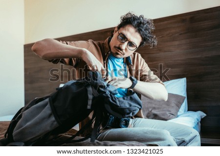 male tourist taking something from backpack in hotel room