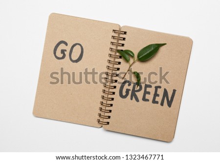 Paper notebook with text GO GREEN on white background