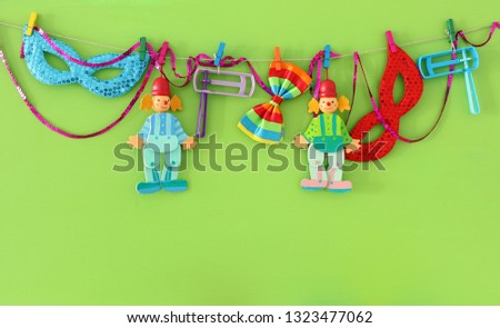 Purim celebration concept (jewish carnival holiday), clowns, masks and noisemaker over wooden green background