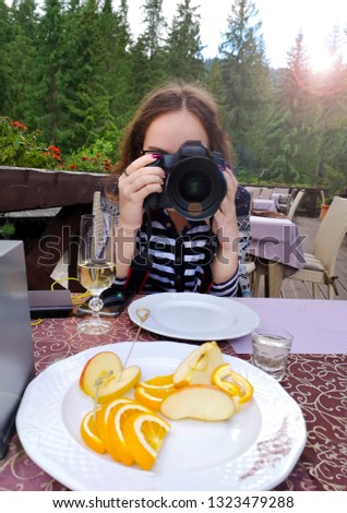 Beautiful girl recording video on camera In the open air restaurant.. Food blogger concept
