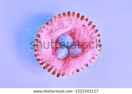 Three Easter eggs with space galactic pattern in a basket with a filler in the form of a pink nest on a blue background. flat lay